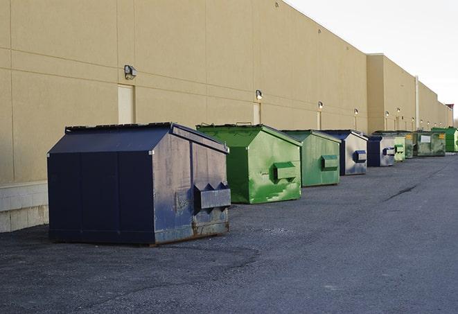 a construction worker empties a wheelbarrow of waste into the dumpster in Athens MI